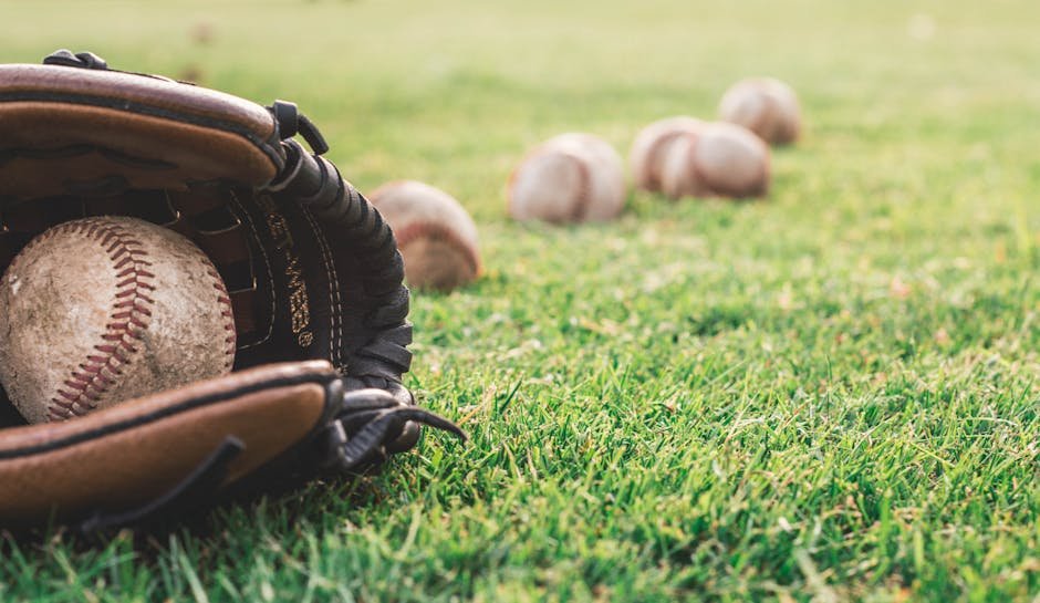 A close-up of a baseball glove with balls on a green field, symbolizing outdoor sports.