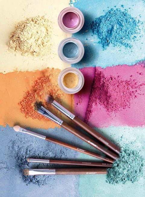 Colorful makeup powders and brushes in an artistic flat lay composition.