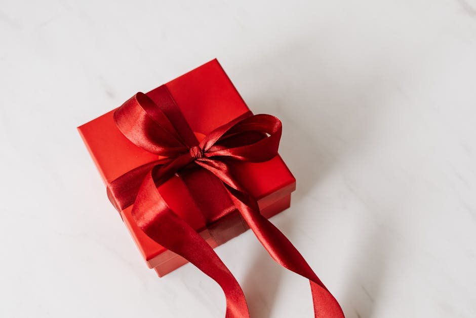 A red gift box with a satin ribbon, perfect for celebrations on a marble background.