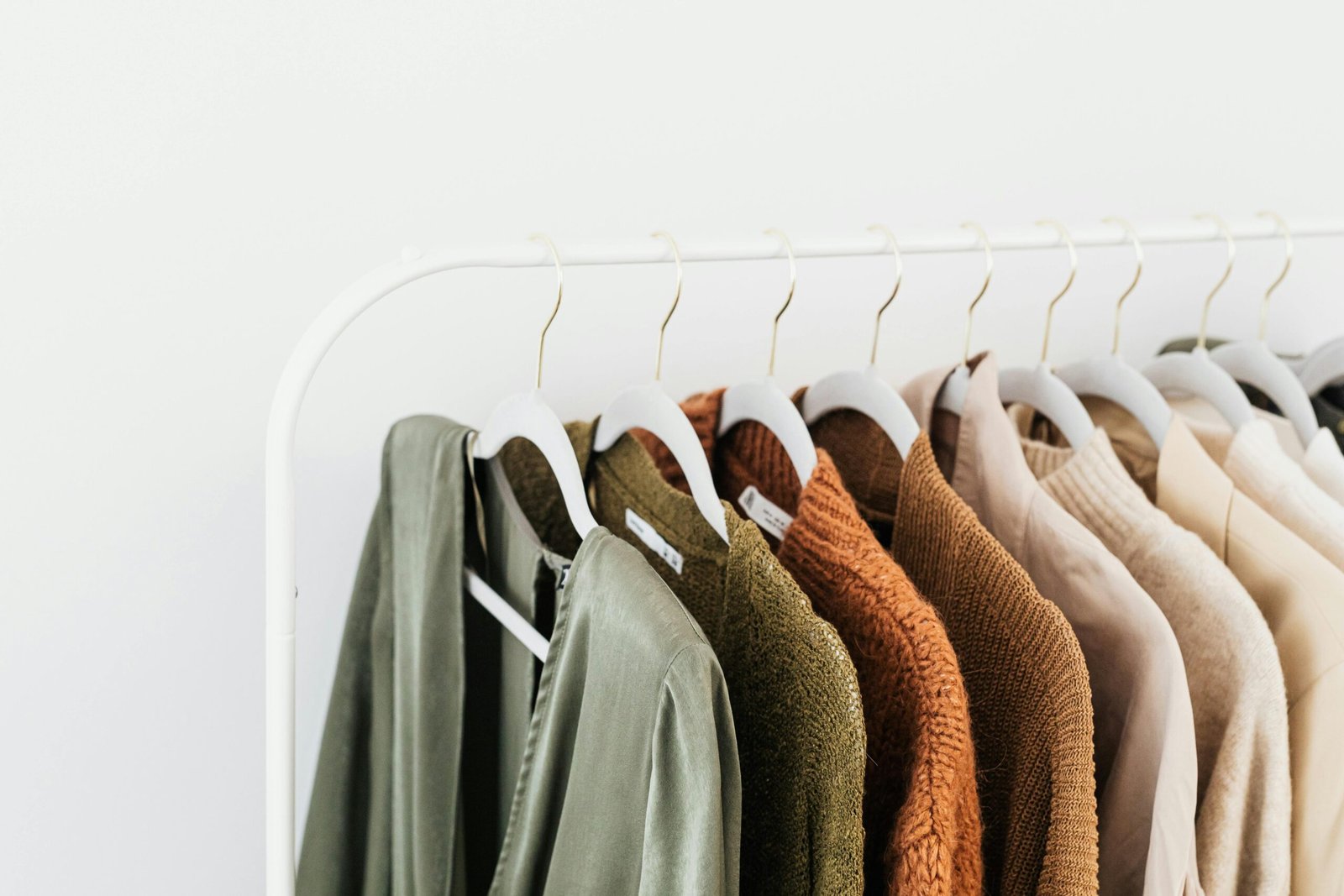 A minimalist display of colorful sweaters and shirts on white hangers.