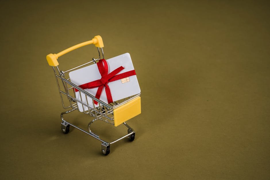 A gift card with a red bow sits in a mini shopping cart on a yellow backdrop.