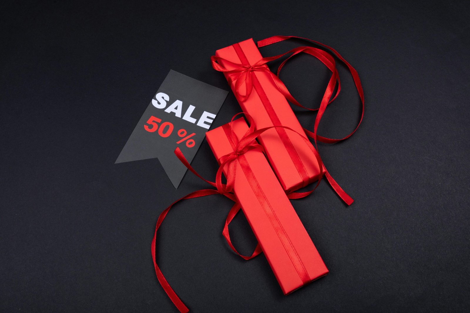 Red gift boxes with ribbons and a 50% sale tag on a dark background.